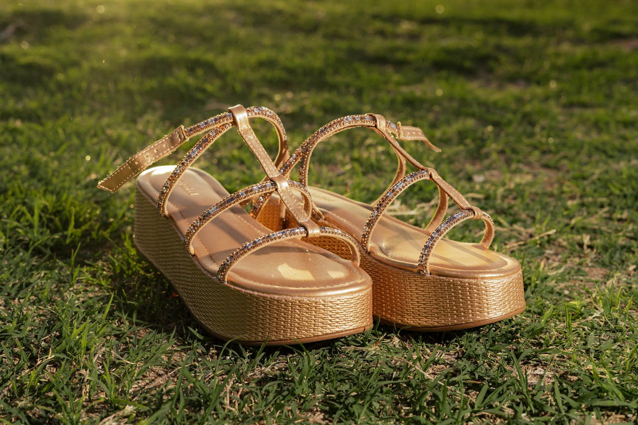 Golden platform sandals with rhinestones showcased on grass, ideal for summer style and fashion shoots.