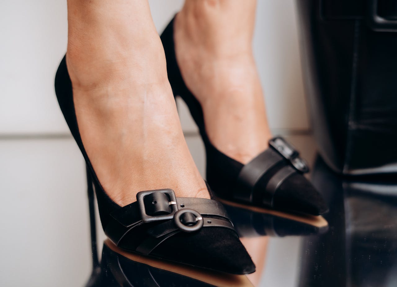Close-up of stylish black high heel shoes with reflections on a glossy surface.