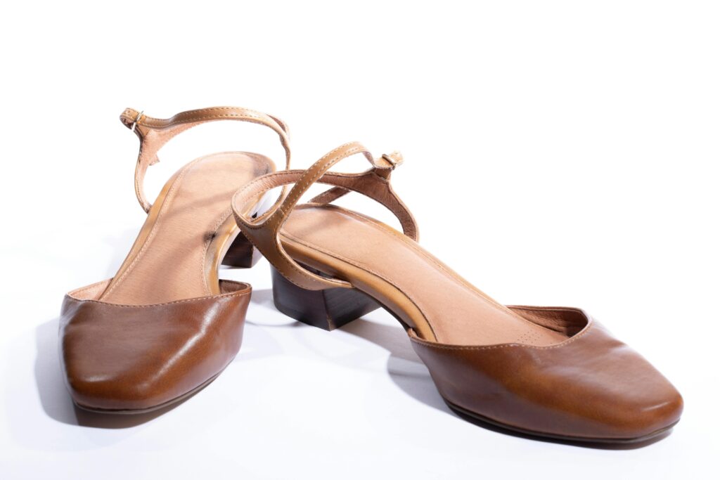 Pair of stylish brown leather strap heeled sandals on a white background.
